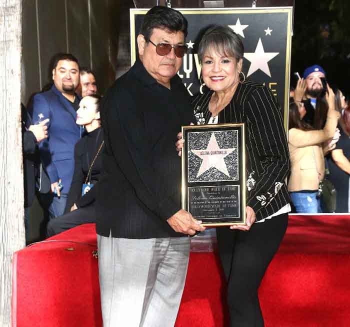 A picture of Abraham and Marcella holding a hall of fame certificate of their late daughter.